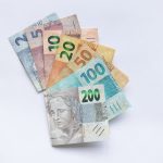 Cédulas de real brasileiro dispostas em leque sobre fundo branco.