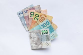 Cédulas de real brasileiro dispostas em leque sobre fundo branco.