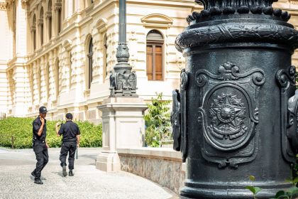Dois agentes de segurança caminham diante de um edifício histórico em São Paulo.