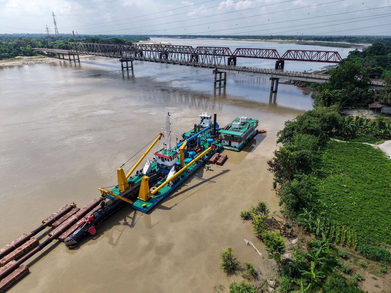 Balsa realiza trabalho de desassoreamento no rio Gorai, próximo a uma ponte em Kushtia, Bangladesh.