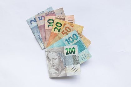 Cédulas de real brasileiro dispostas em leque sobre fundo branco.