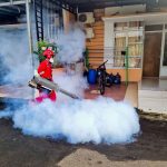Profissional de controle de pragas usa uma máquina de fumacê do lado de fora de uma casa.