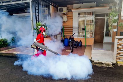 Profissional de controle de pragas usa uma máquina de fumacê do lado de fora de uma casa.